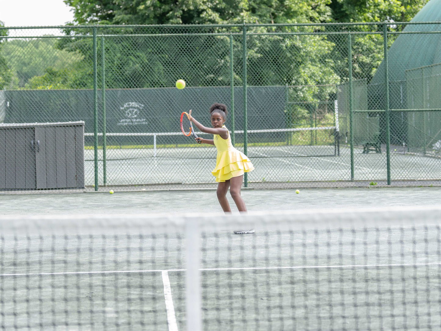 Young girl playing tennis in a lightweight, breathable Love U Bunches dress